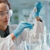 person in a lab squeezing something into a beaker