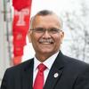 headshot of Dean Madhavan with Temple flags